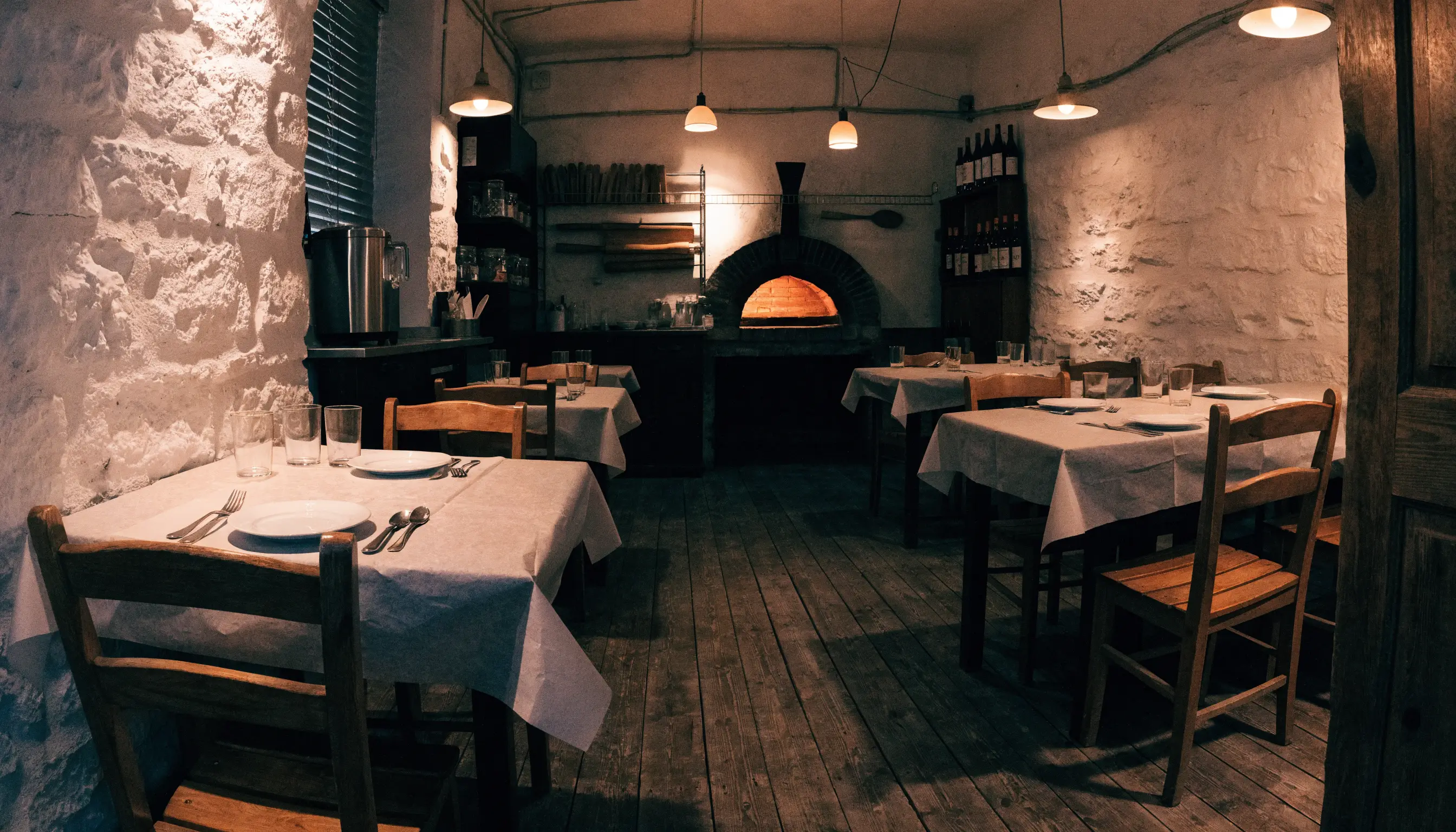 La sala della pizzeria con il forno a legna sul fondo
